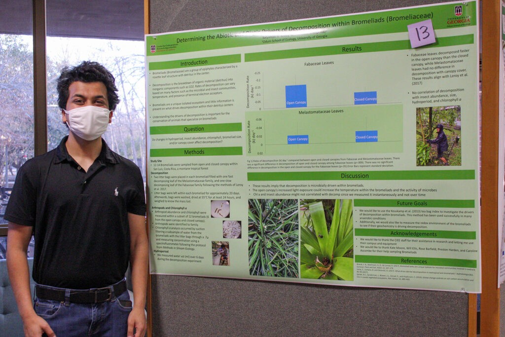 Odum student Tejas Reddy stands next to his undergraduate ecology research poster "Determining the Abiotic and Biotic Drivers of Decomposition within Bromeliads (Bromeliaceae)." Photo: Catherine Campbell.
