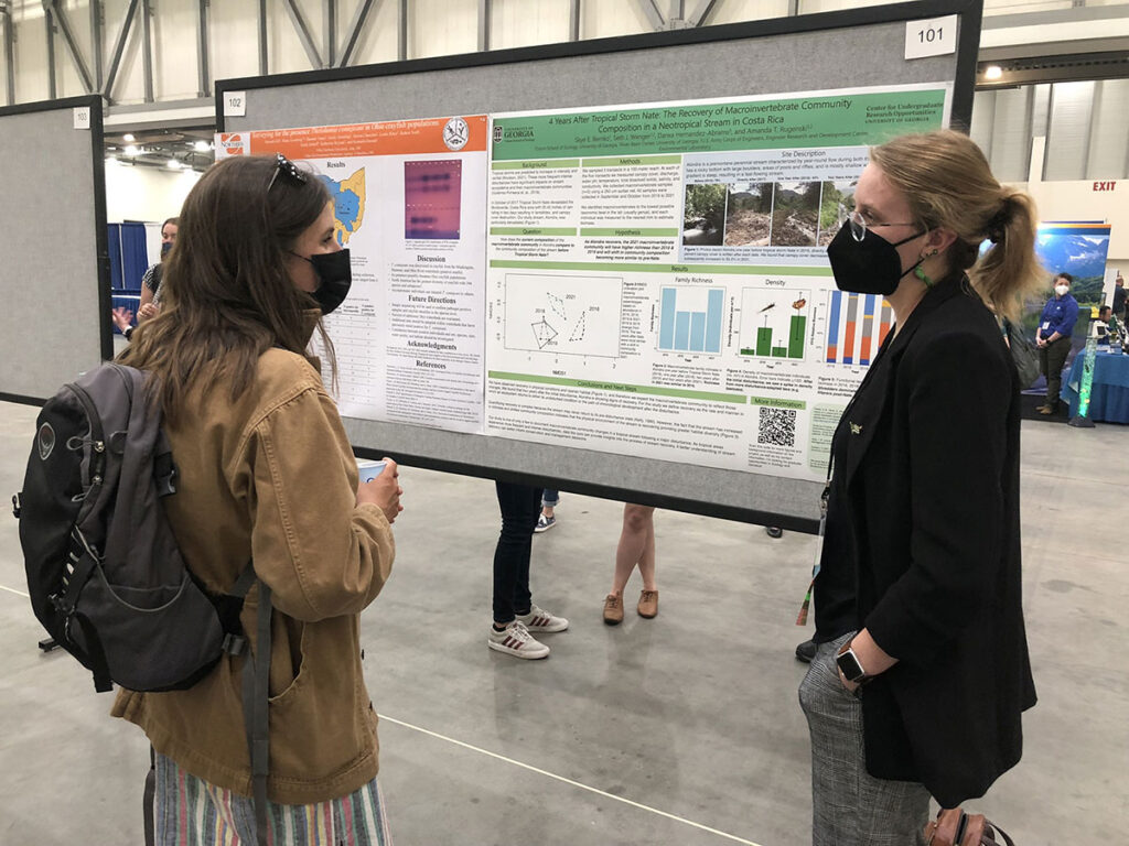Odum student Skye Remko (right) discusses her undergraduate ecology research poster "4 Years After Tropical Storm Nate: The Recovery of Macroinvertebrate Community Composition in a Neotropical Stream in Costa Rica" with recent graduate Kelsey Solomon at the 2022 Joint Aquatic Sciences Meeting.