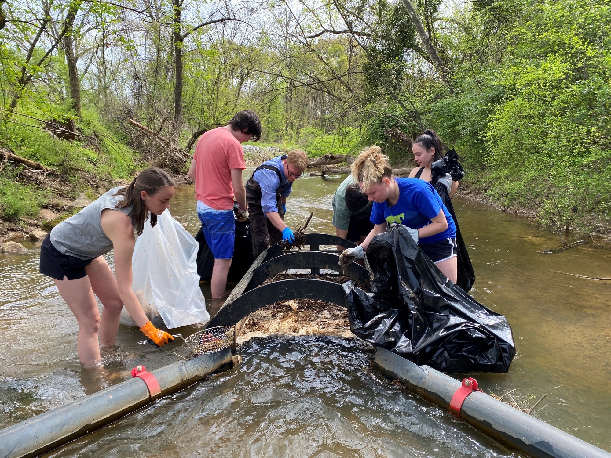 students in stream cleaning trash